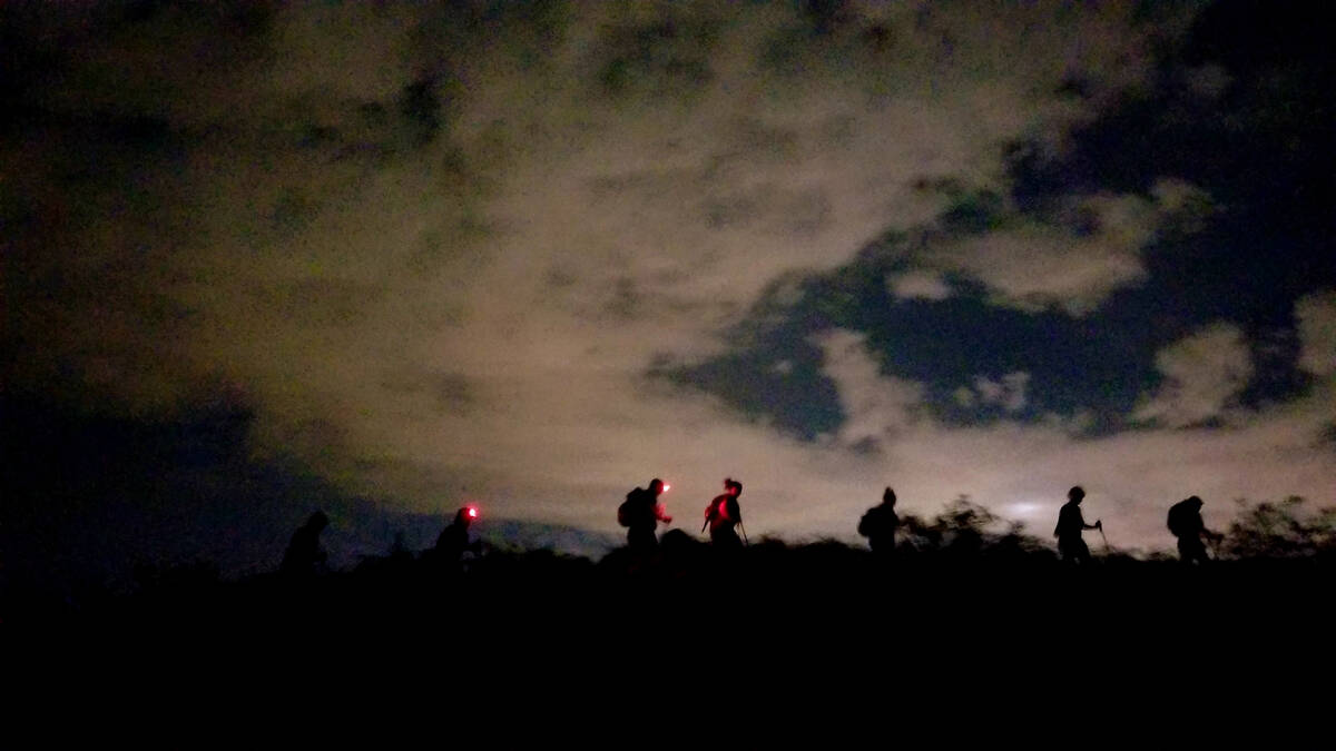 Summer night hikers silhouetted along a path in Sloan Canyon National Conservation Area. Las Ve ...