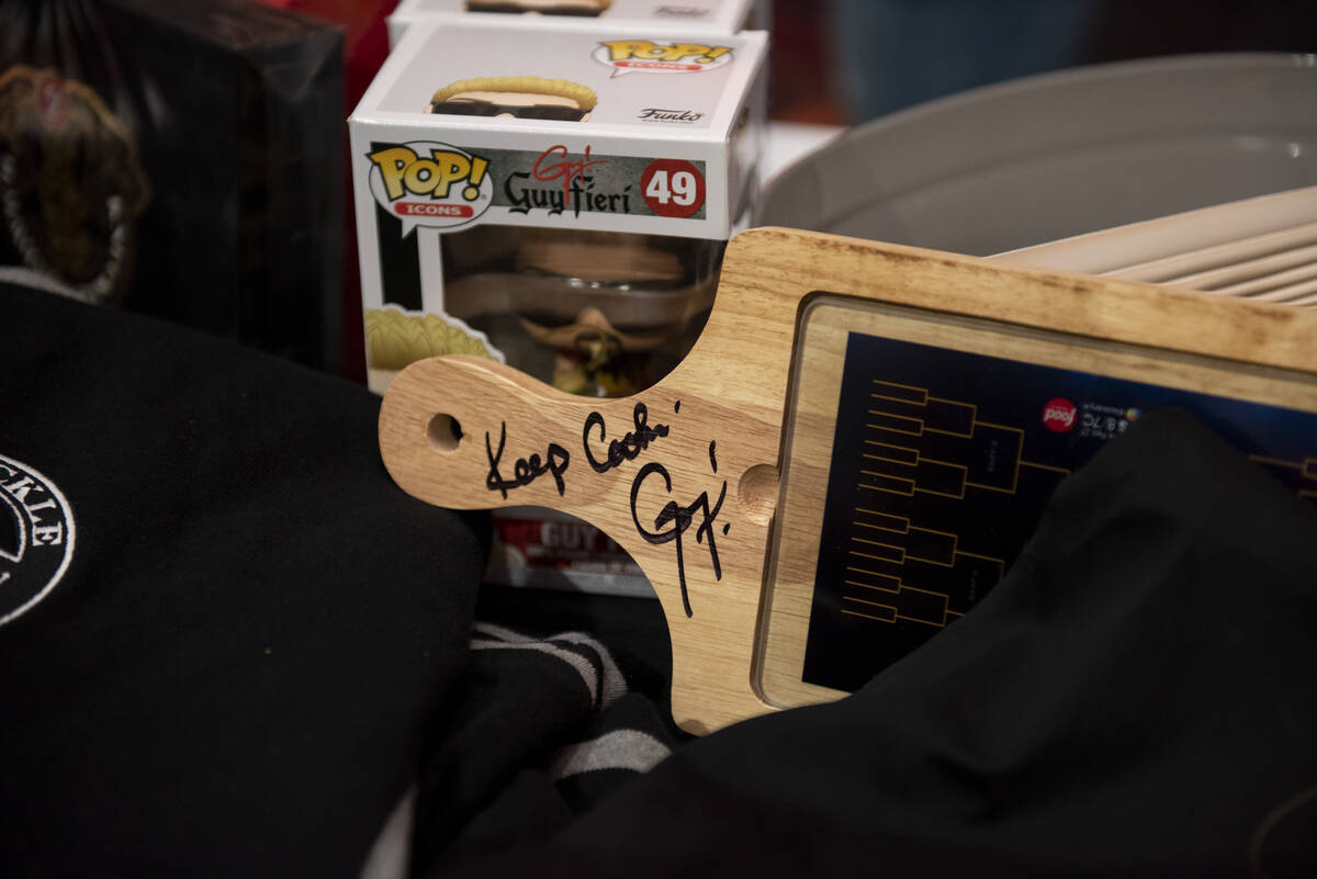 Raffle items including Funko POP! figurines, clothing, and kitchen items sit on a table for dis ...