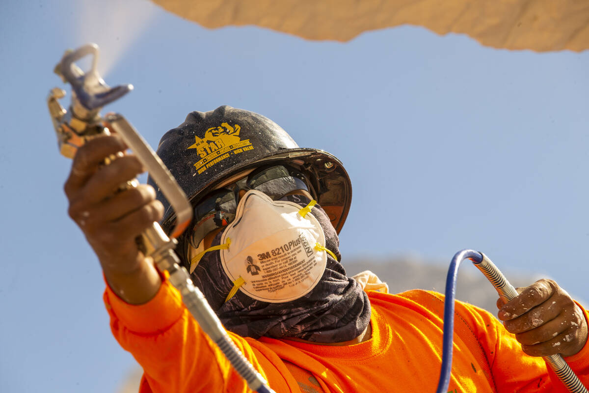 Jose Cervantes with the Vergith Contracting Co. begins to add a white finish color to a totem a ...