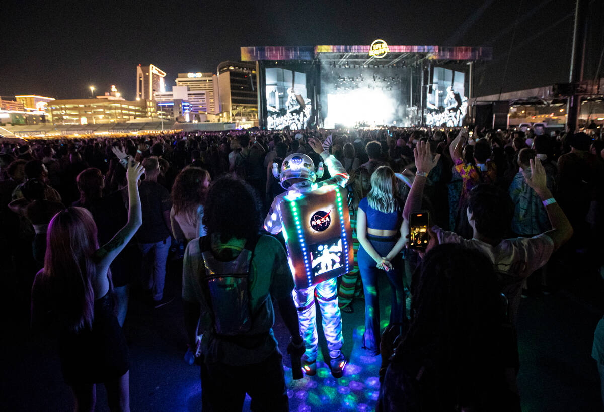 An attendee dressed up in a space suit cheers as Cage the Elephant performs during the first da ...