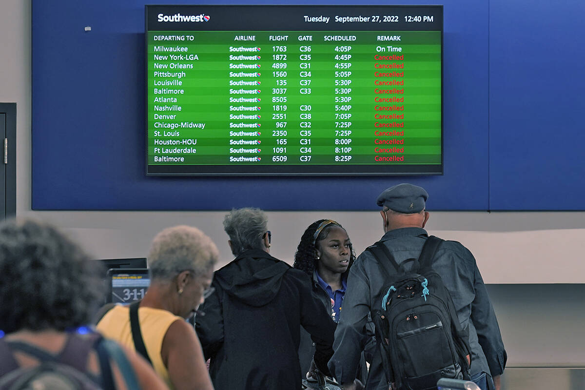 Southwest Airline passengers check into a ticket counter near a sign that shows canceled flight ...