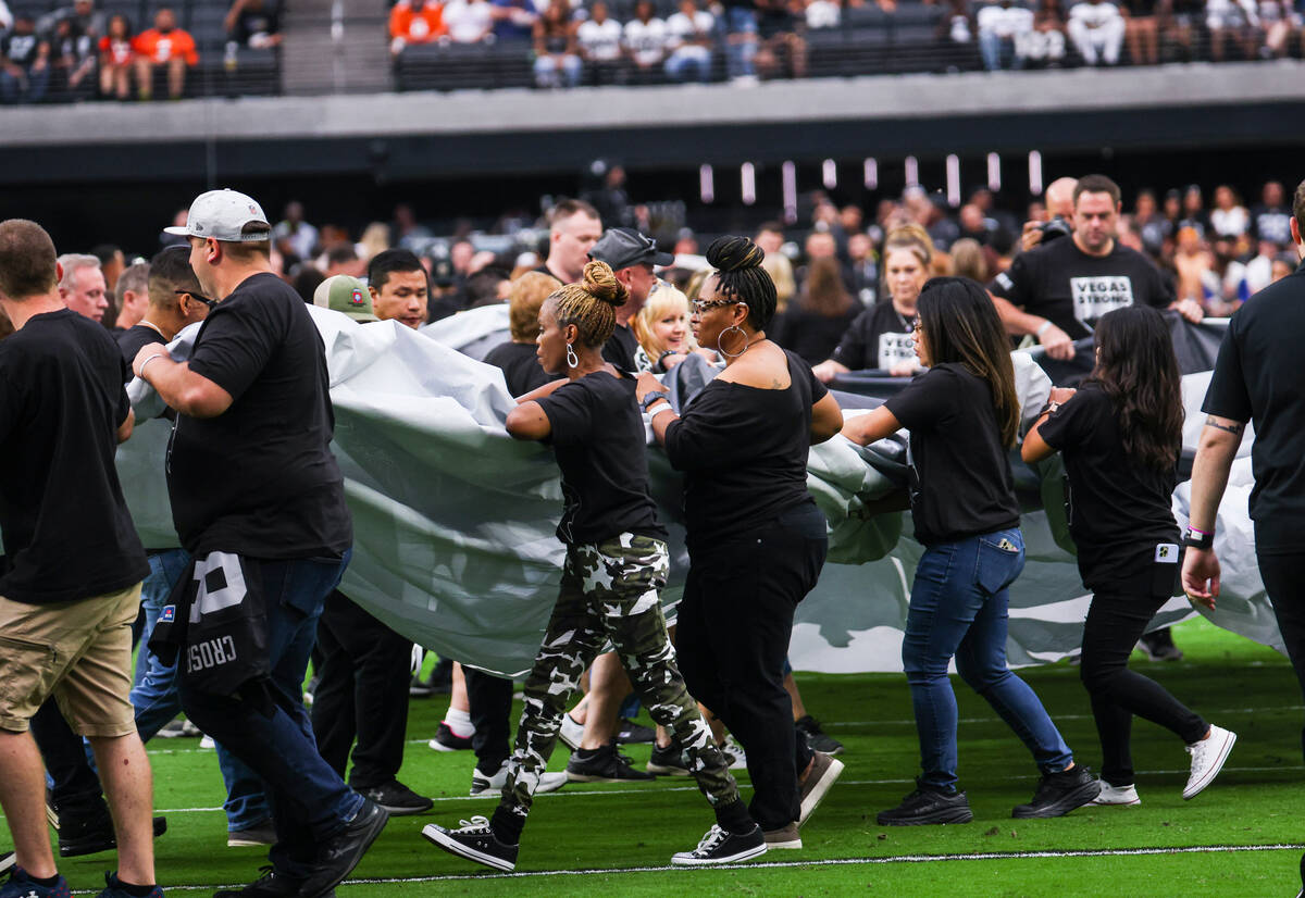 People carry out a Vegas Strong flag before the start of an NFL game between the Raiders and De ...
