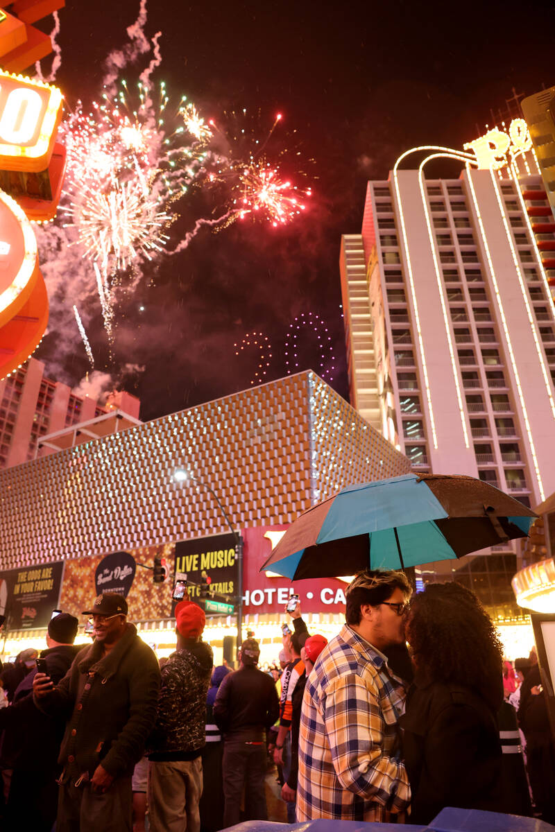 Angel Gonzalez and Tae Haley share an umbrella during a fireworks and drone show above the Plaz ...