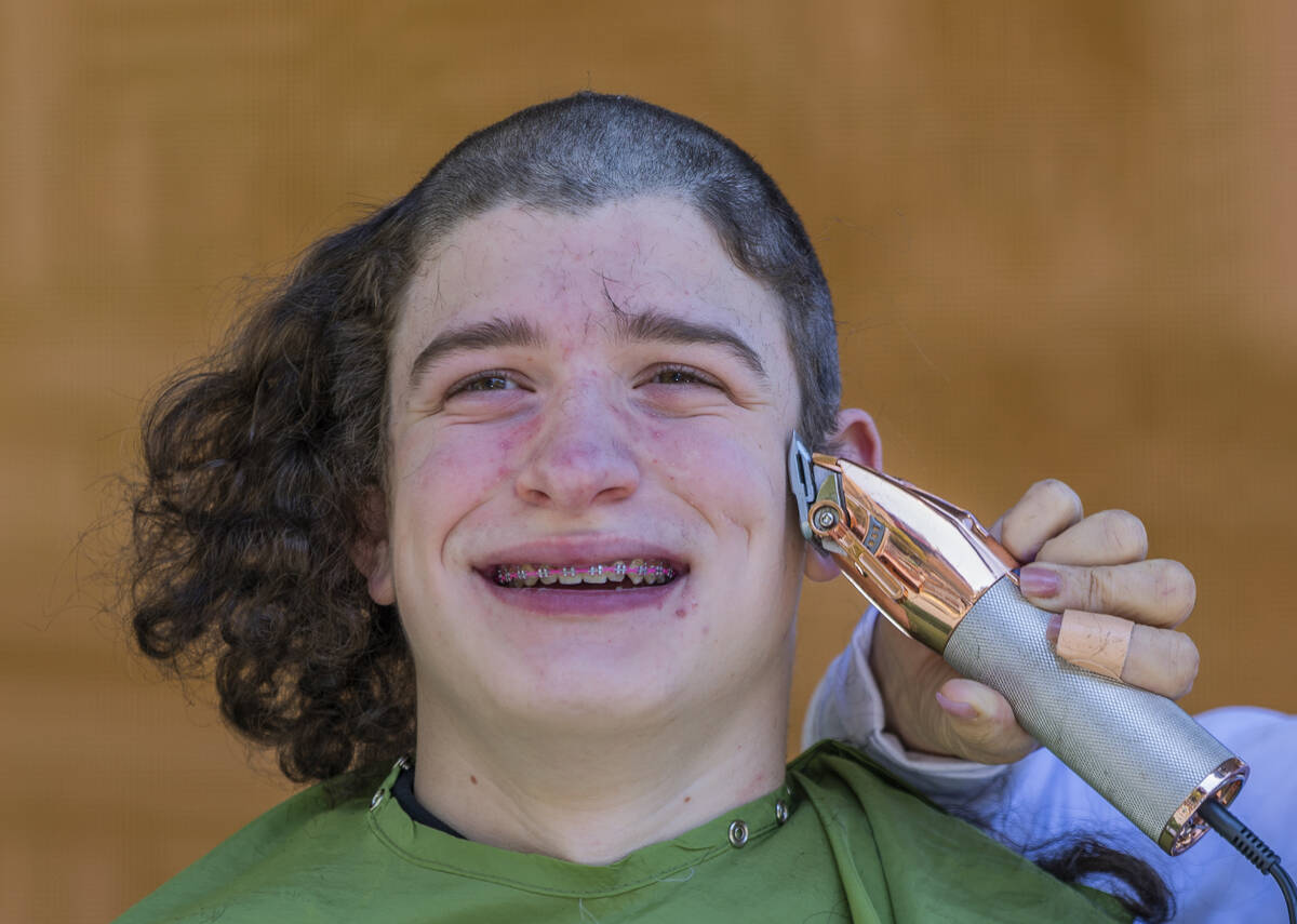 Declan Alvarez with a group from the Clark County Schools has his long hair shaved by a stylist ...