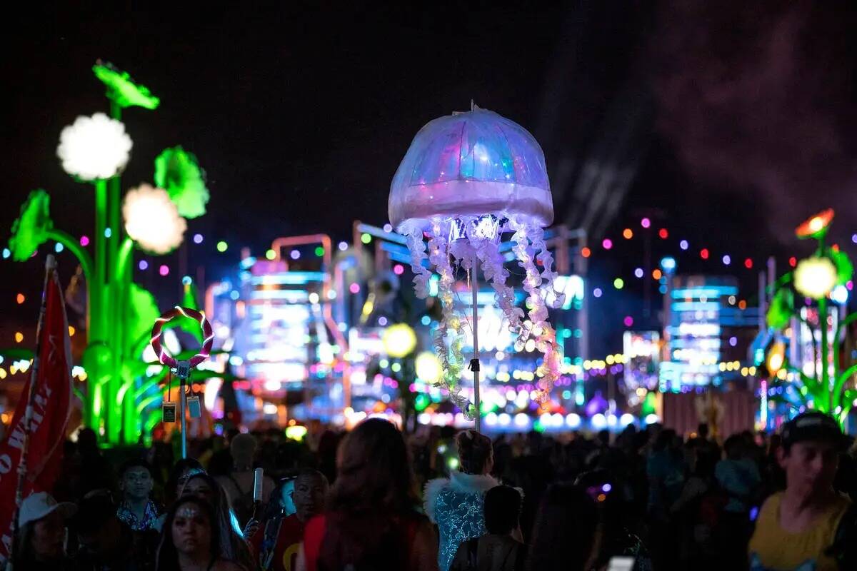 An attendee leads his group through the crowd with a jellyfish umbrella during the second day o ...