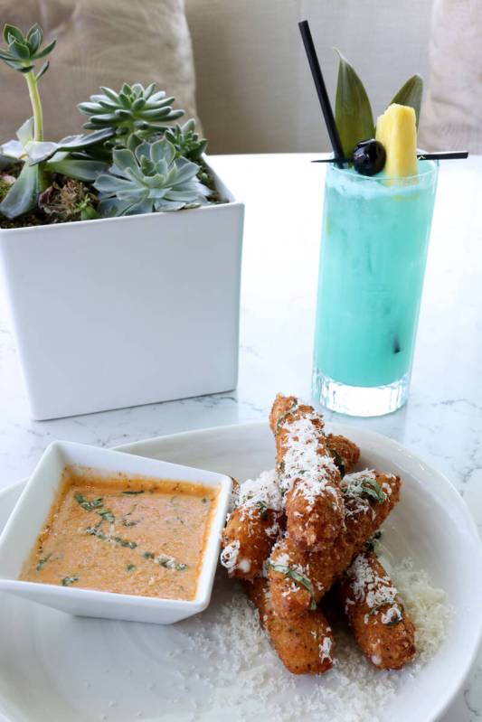 Provolone Fritto appetizer and Laguna Blue signature cocktail are shown at Laguna Pool House &a ...
