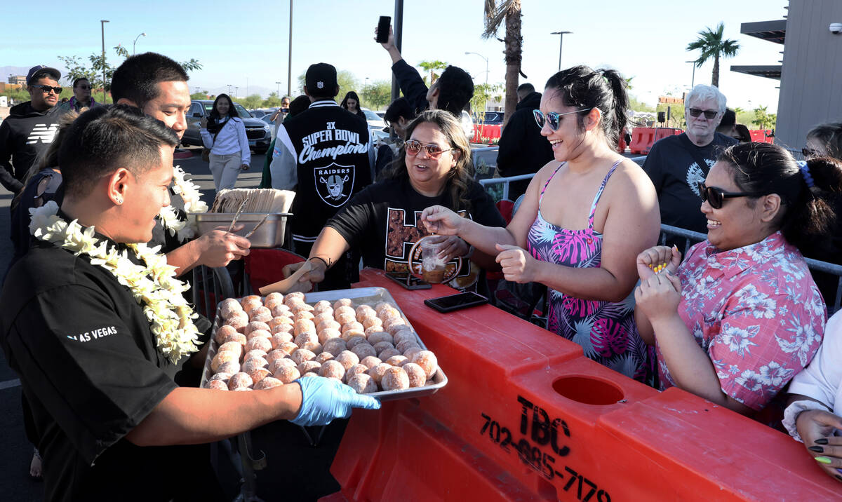 Jan Dale, from left, Tifanie Silver and Peanut Dela Cruz, all of Las Vegas, grab malasadas near ...