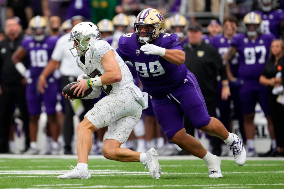 Oregon quarterback Bo Nix is tackled by Washington defensive lineman Faatui Tuitele (99) during ...