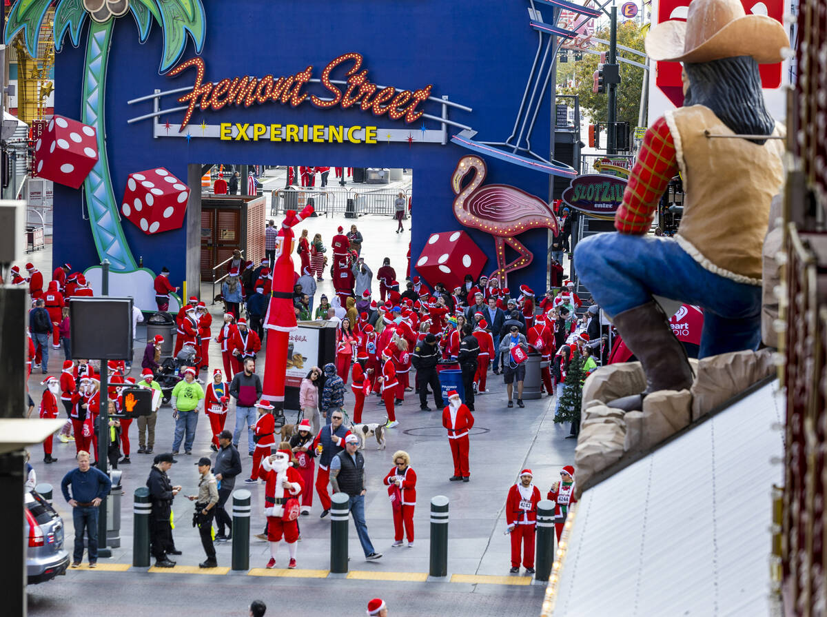 Participants clad in Santa outfits arrive for the pre-race entertainment at the Fremont Street ...