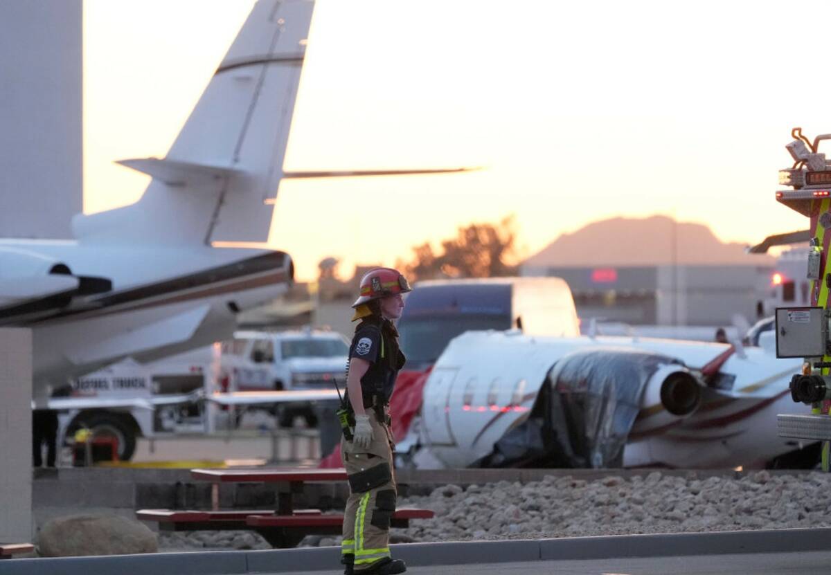 A member of the Scottsdale Fire Department stands near a crashed Learjet at Scottsdale Airport ...