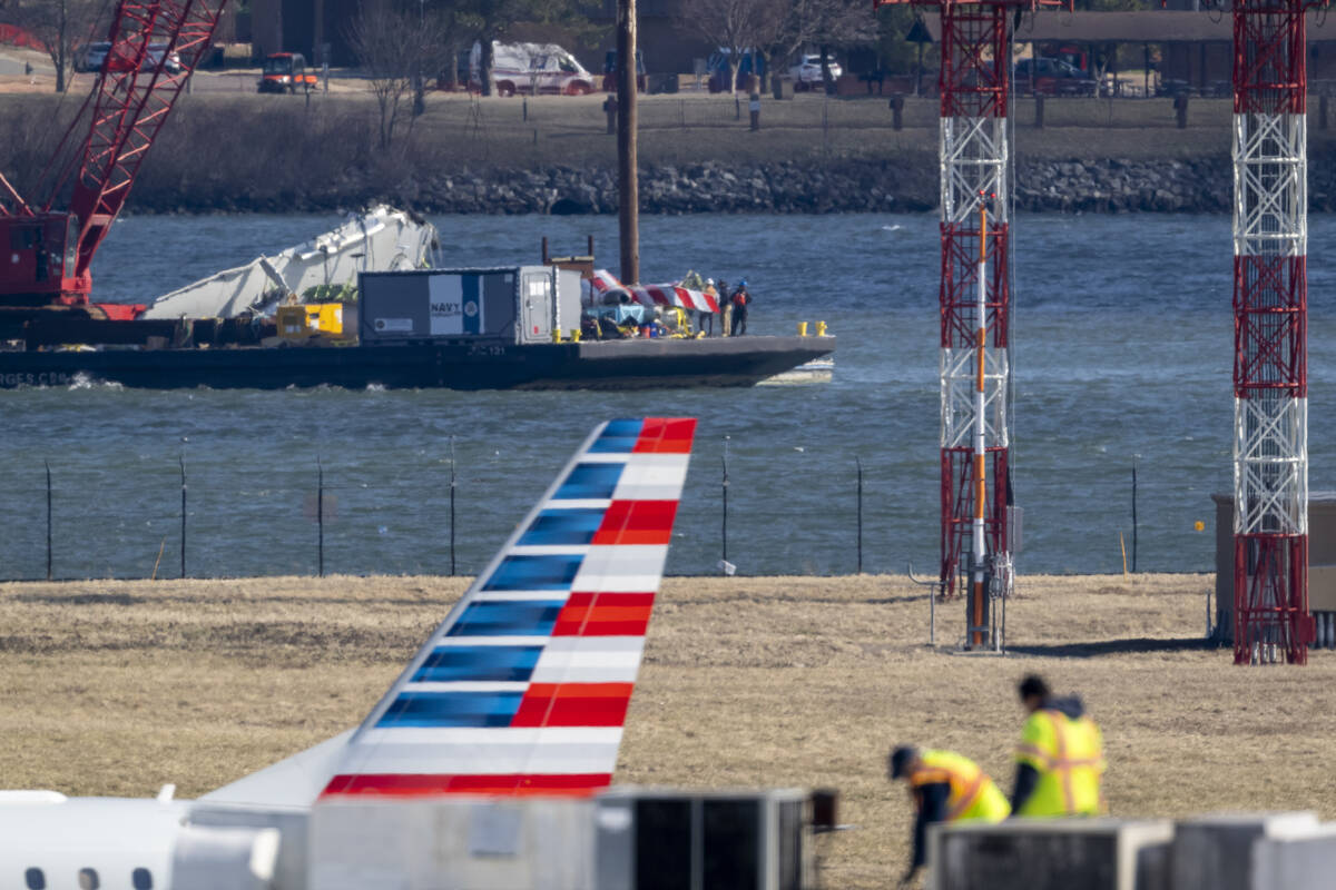 Parts of a plane are lifted from the water near the wreckage site in the Potomac River of a mid ...