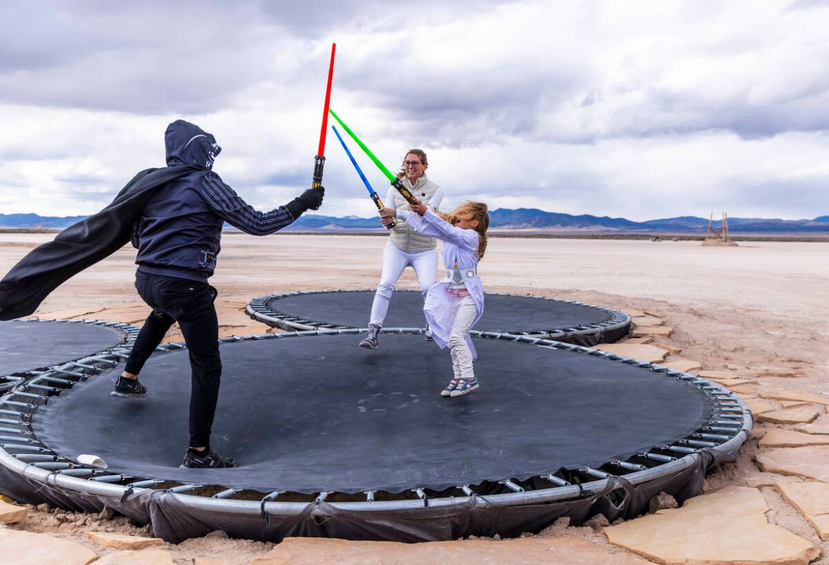 Barry, Melissa and daughter Evie, 6, Ray of Dallas, battle with light sabers atop of trampoline ...