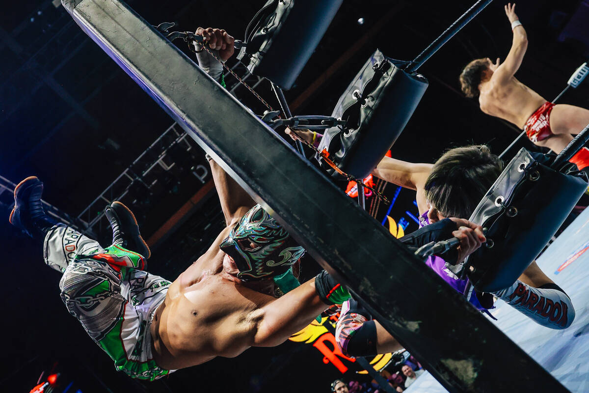Dragon Kid, a Japanese wrestler, hangs on to the side of the wrestling ring during Dragon Gate ...
