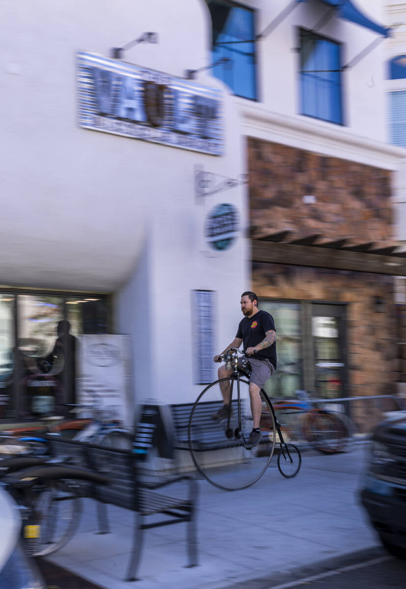 Mechanic Chris Bernardi rides a penny-farthing bicycle past the Vault Bicycle Shop which has a ...
