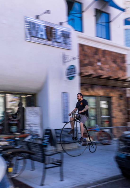 Mechanic Chris Bernardi rides a penny-farthing bicycle past the Vault Bicycle Shop which has a ...