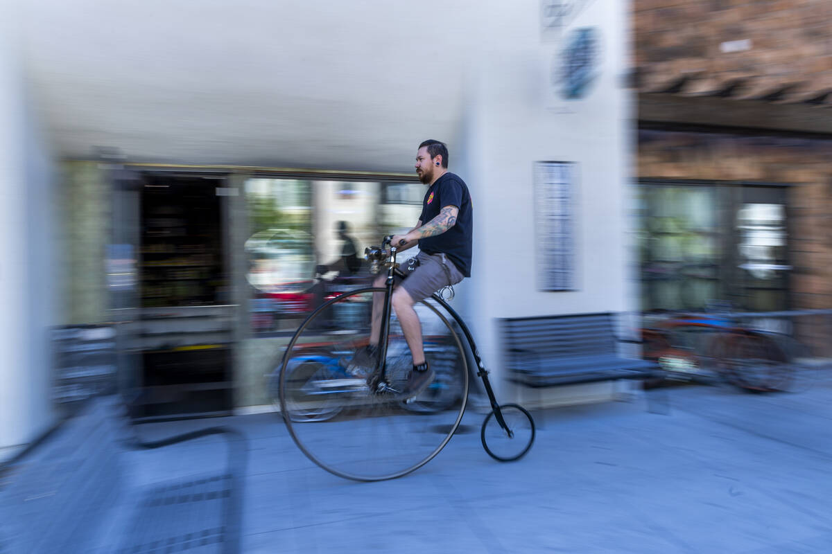 Mechanic Chris Bernardi rides a penny-farthing bicycle past the Vault Bicycle Shop which has a ...
