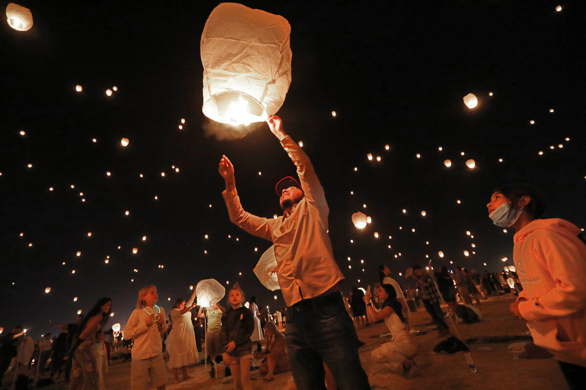 Guillermo Garcia of Los Angeles , center, releases his lantern at the Rise Festival in the Moja ...