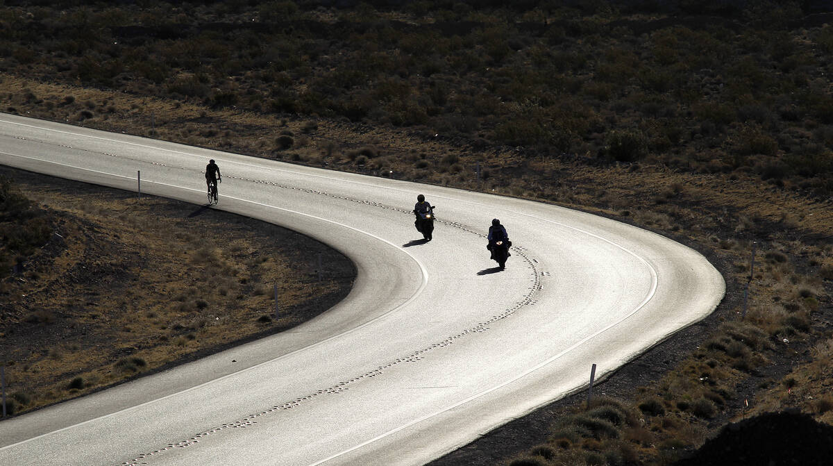 Shortly after sunrise bikers ride toward the Red Rock Canyon National Conservation area outside ...