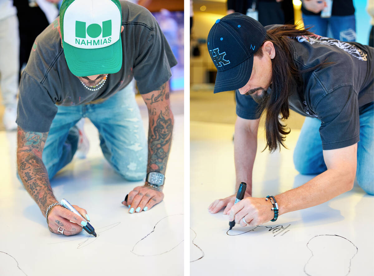 Backstreet Boys members AJ McLean, left, and Kevin Richardson, right, sign spots on the floor a ...