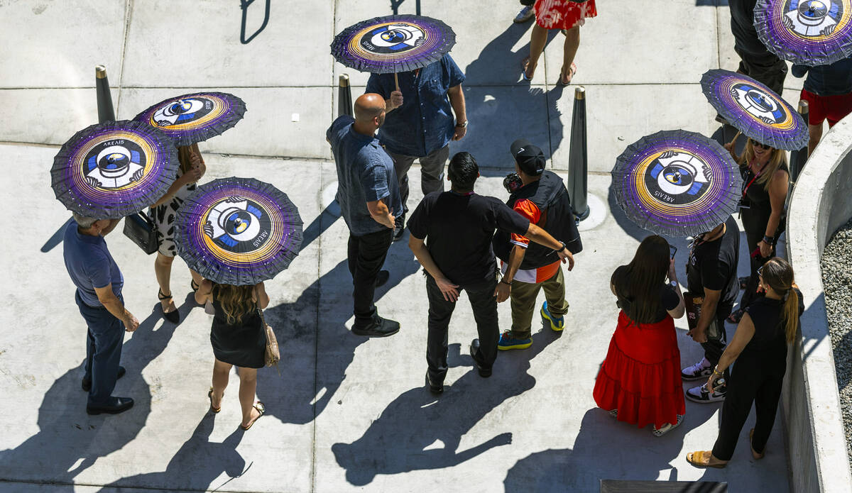 Attendees use parasols to block the sun while awaiting the start of an opening ceremony for Zon ...