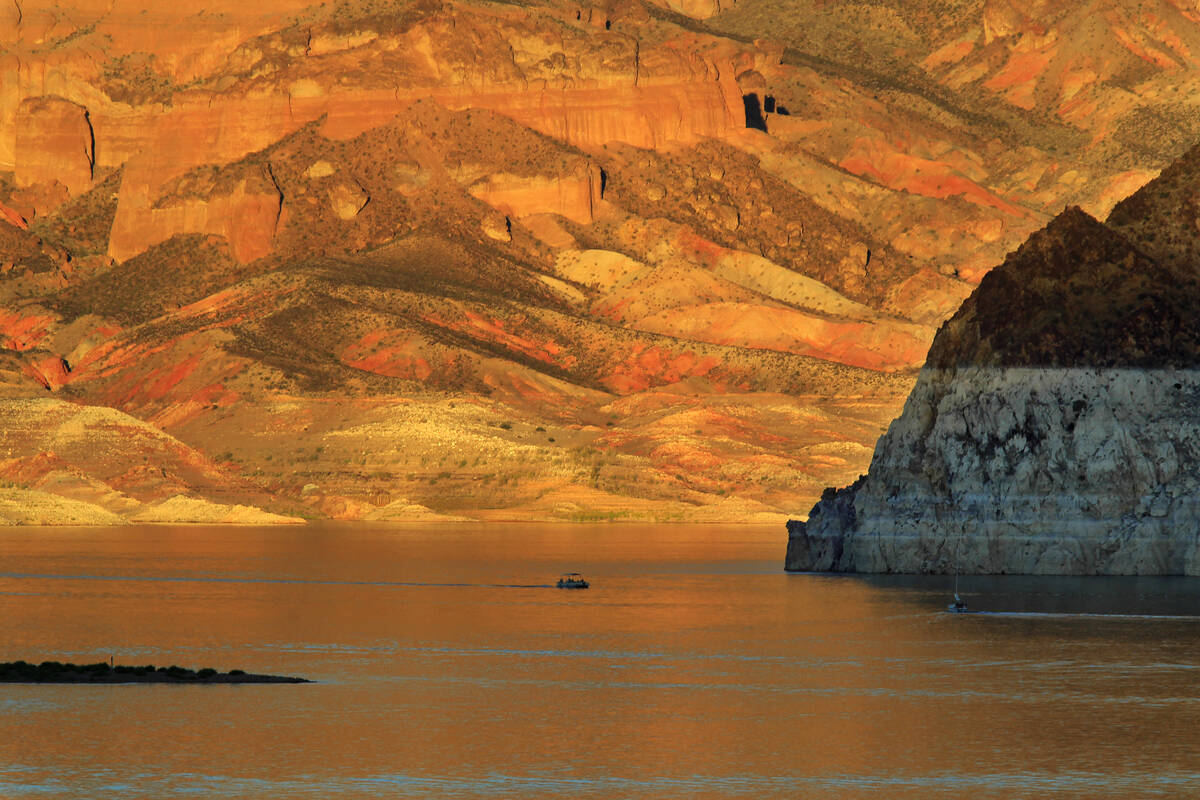A boat plies the waters of Lake Mead as the setting sun lights up Painters Cove Monday, Oct. 6, ...