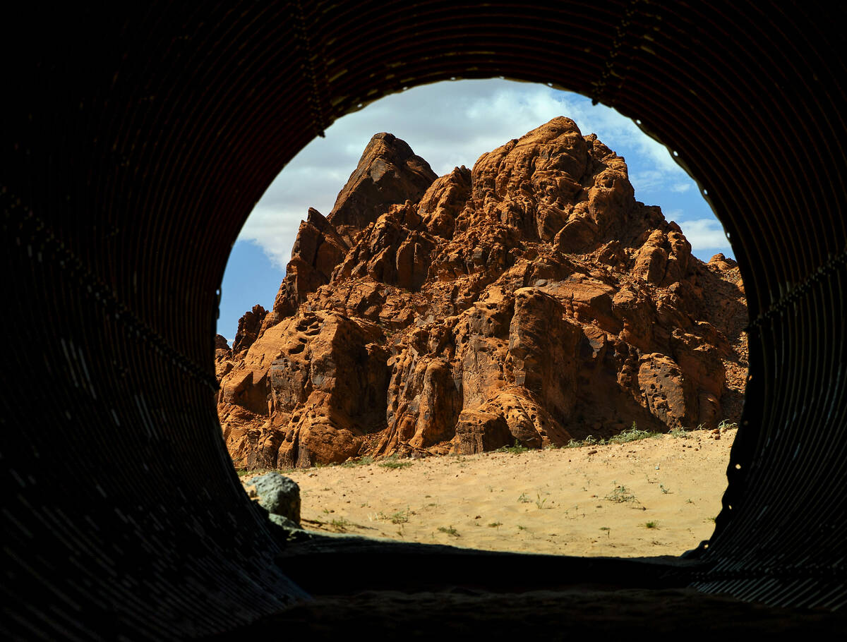 Red rock is framed in a tunnel leading to Charlie's Spring in the Valley of Fire State Park on ...
