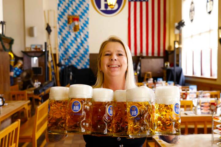 Roxy, a server and restaurant supervisor, holds glasses of beer as she poses for a photo at Hof ...
