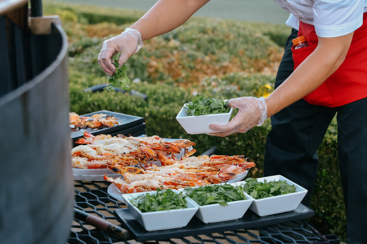 A cook sprinkles garnish atop cooked prawns during Revelry’s The Feast on Saturday, Sept ...
