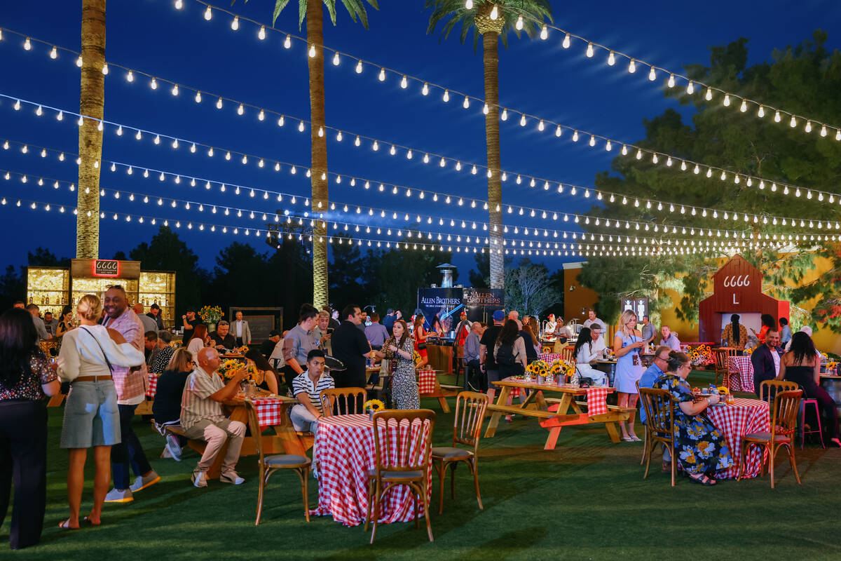 Guests dine on the lawn around the Four Sixes cookout booths during Revelry’s The Feast ...