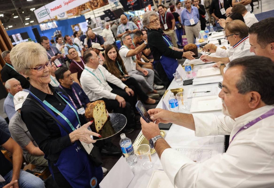 Judge and pastry chef Biagio Settepani, right, takes a photo of fresh panettone held by volunte ...