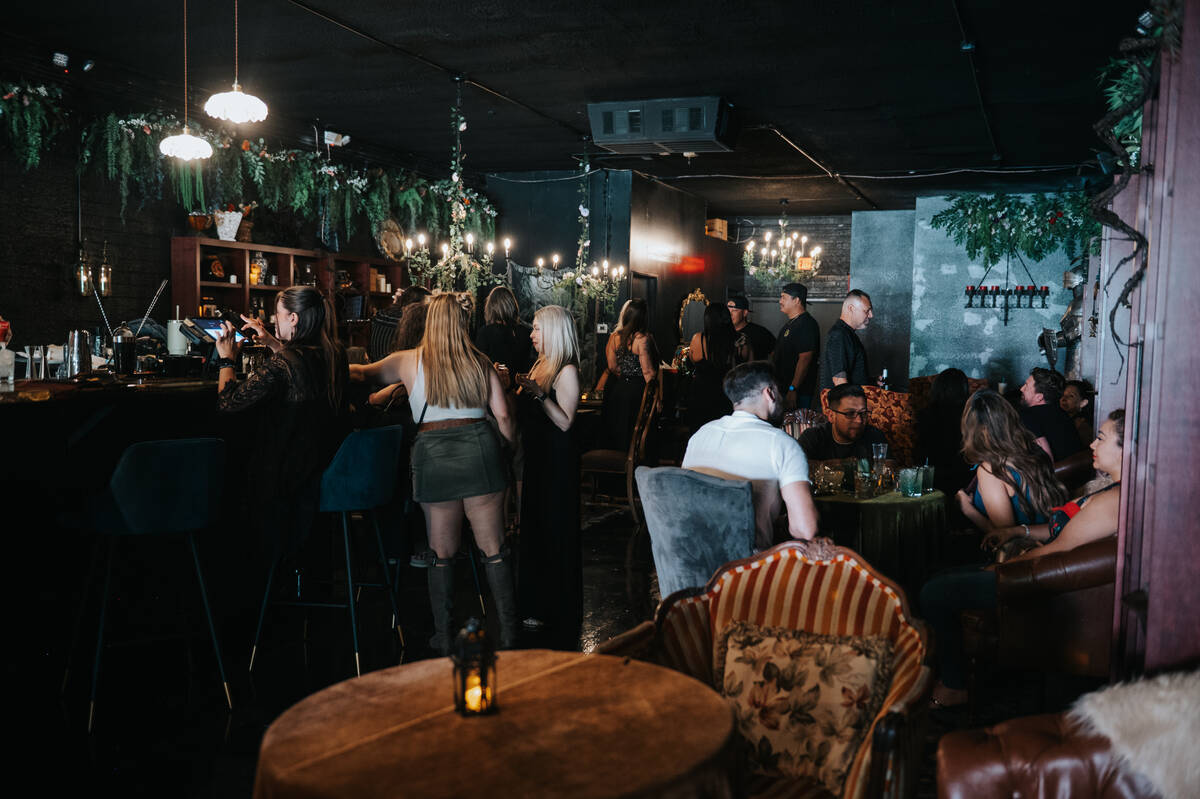 Inside, guests step into a candlelit lounge lined with velvet seating, twisting greenery and a ...
