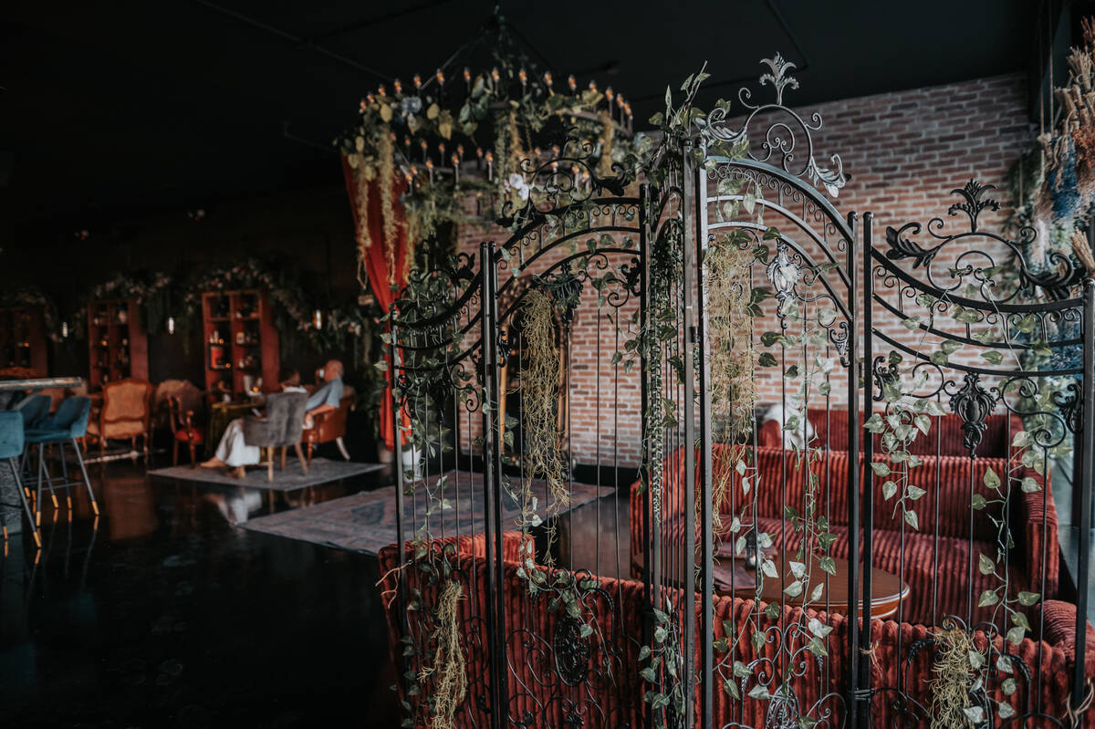 Inside, guests step into a candlelit lounge lined with velvet seating, twisting greenery and a ...