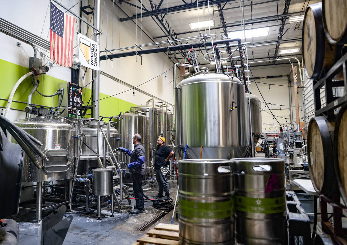 Employees Cameron Fisher, left, and Mono Donis, right, clean equipment in the brewery at CraftH ...