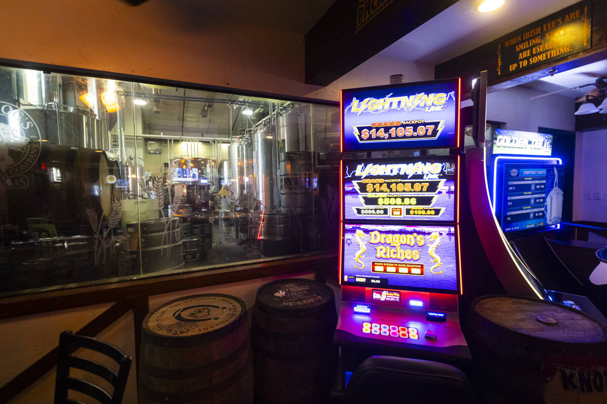 A window looking into the brewing room is seen next to a slot machine at Big Dog’s Draft Hous ...