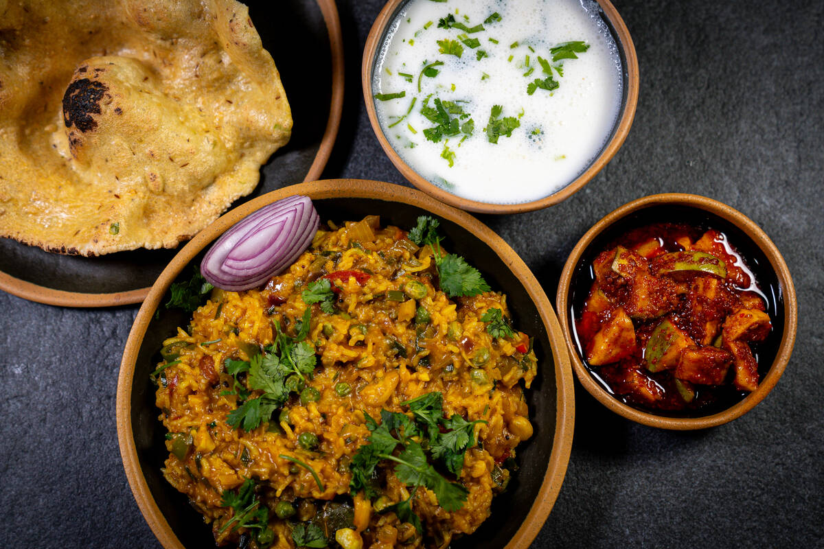 Vaghareli kichdi, a Gujarati stew of rice, lentils, vegetables and spices, front, and papadi de ...