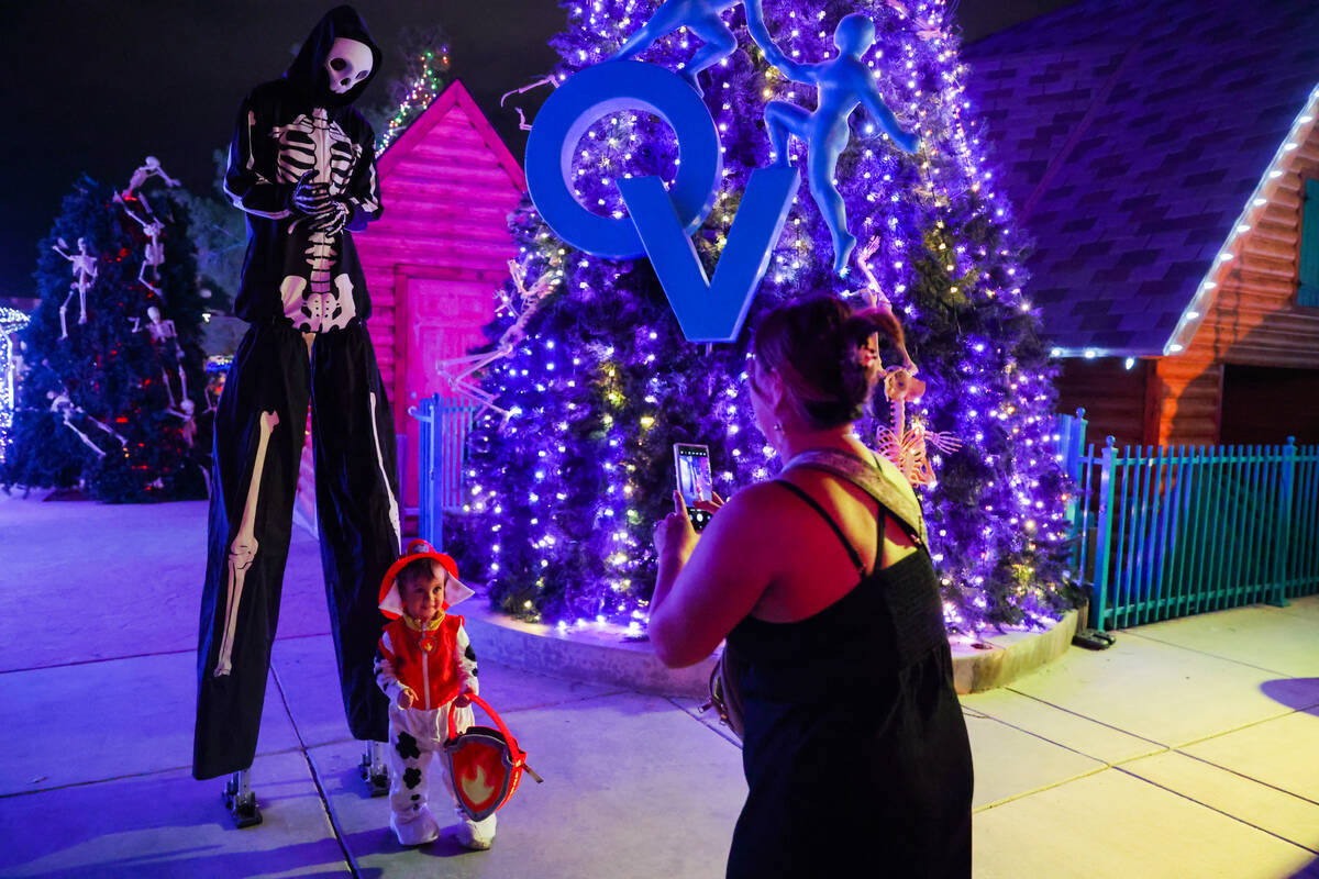 Easton Scholl, 2, middle, gets his picture taken with a skeleton on stilts by his mother, Tiann ...