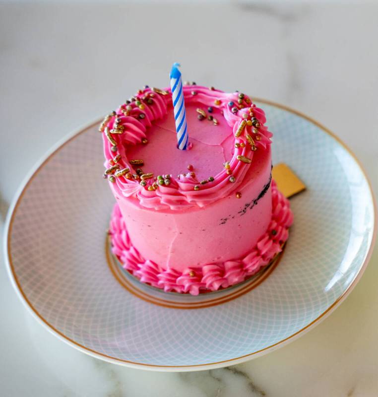 A birthday cake waits to be served during Peacock Alley’s Pink Ribbon Tea, an afternoon ...