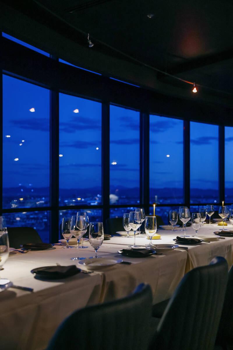 Tables are set against the backdrop of an evening skyline view at High Steaks at Rio Hotel &amp ...