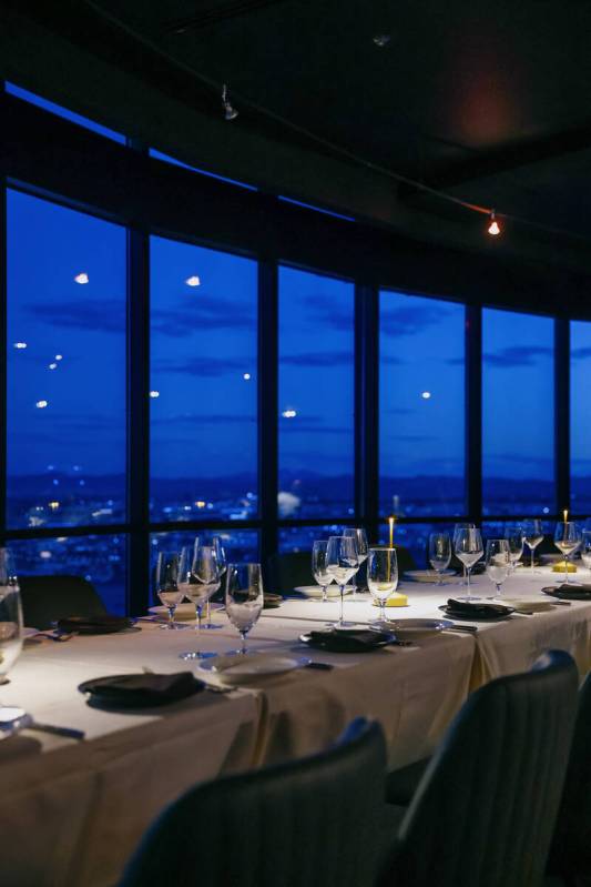 Tables are set against the backdrop of an evening skyline view at High Steaks at Rio Hotel &amp ...