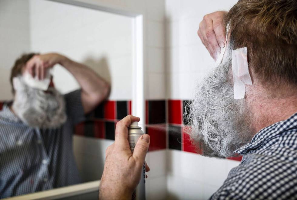 Chef Robert Teddy, owner of Wicked Donuts, finishes spraying white Kryolan make up on his beard ...