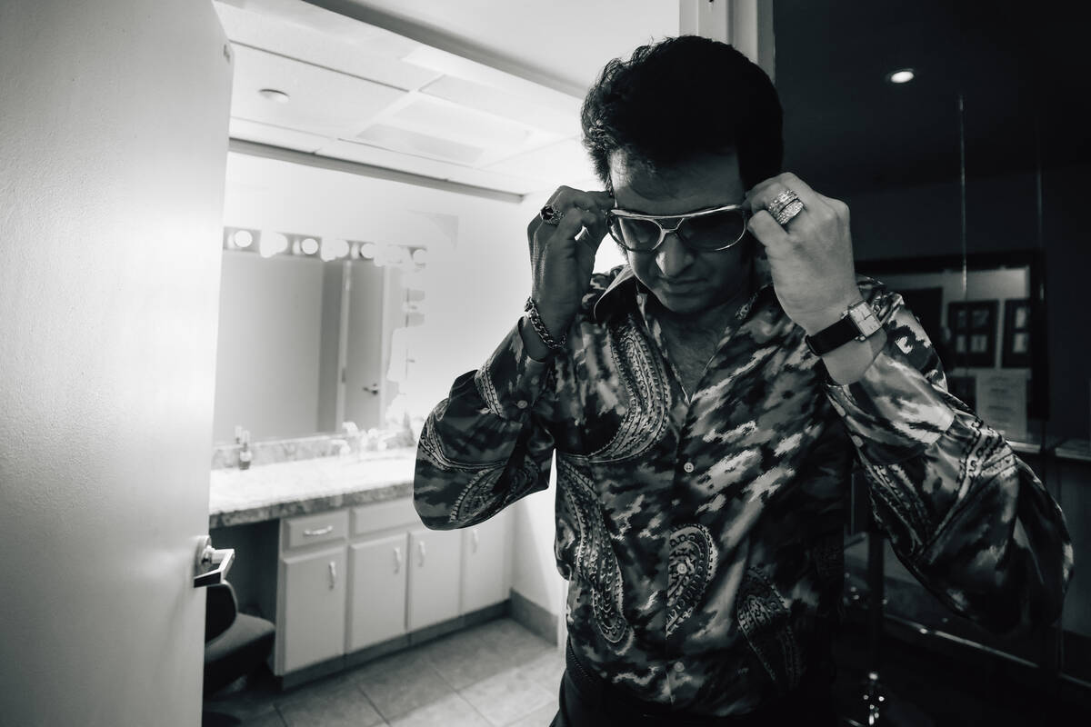 Travis Powell, an Elvis tribute artist, puts his glasses on in his green room before performing ...