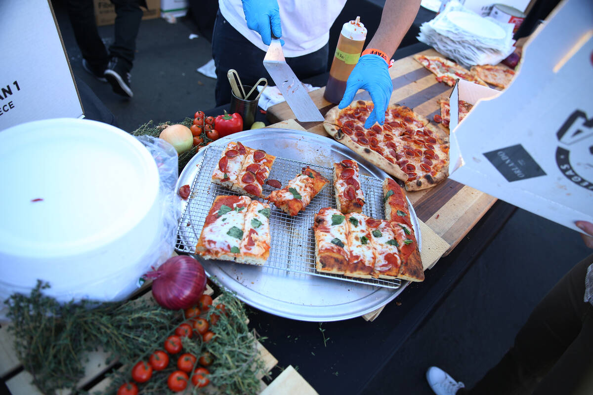 Enzo Esposito, left, executive pizza chef for Side Piece Pizza, serves a slice of pizza during ...