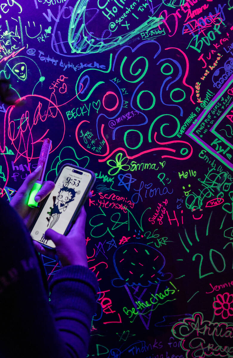 Fans sign a neon art wall before Good Charlotte preforms during the Neon City Music Festival at ...