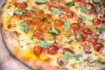 A freshly cooked Olde New York specialty pizza, made with thick slices of mozzarella, old schoo ...
