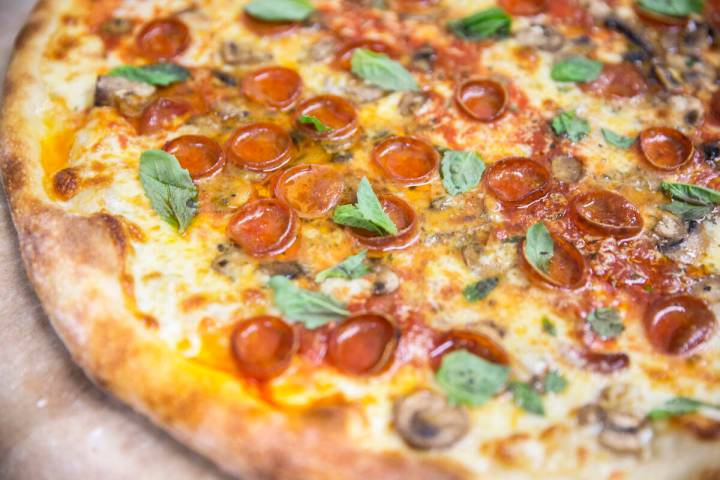 A freshly cooked Olde New York specialty pizza, made with thick slices of mozzarella, old schoo ...