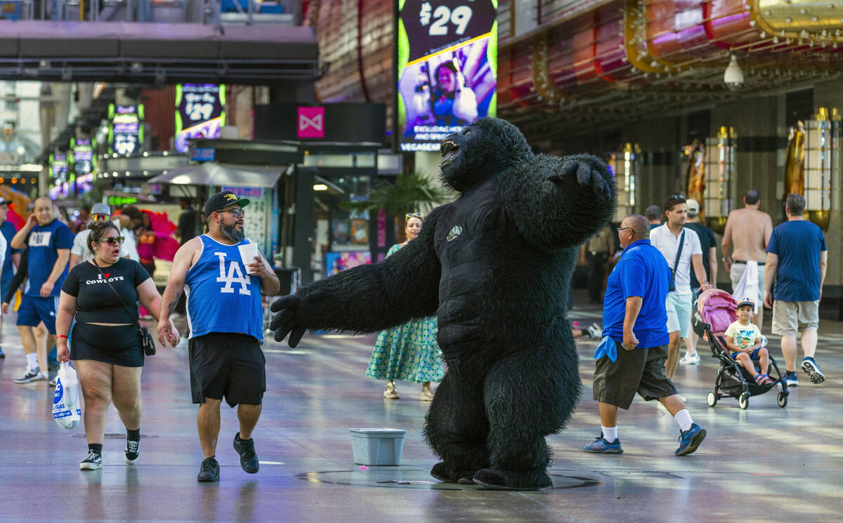 Visitors are surprised by a giant dancing gorilla as a street performer works about the Fremont ...