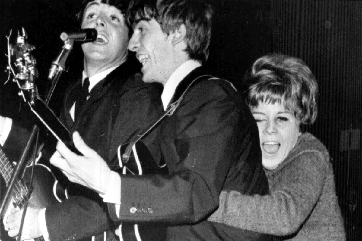 A young Swedish fan hugs George Harrison as The Beatles play at a pop festival in Stockholm, Sw ...