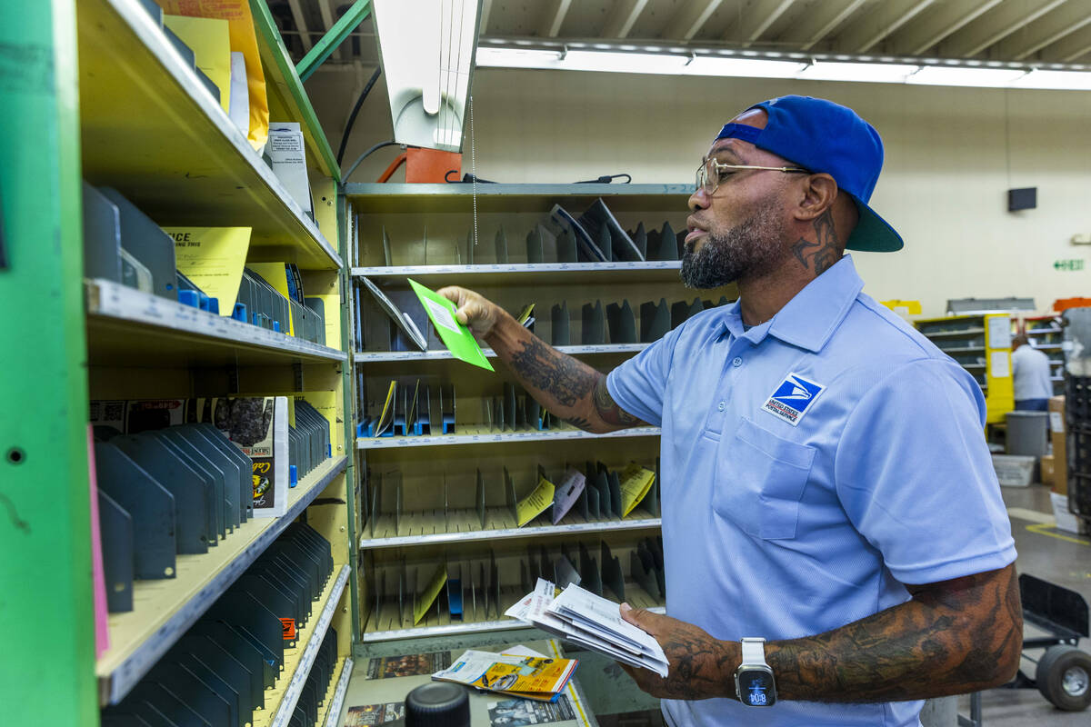 Ishe Smith sorts the mail he will deliver on his route as a mail carrier while starting his shi ...
