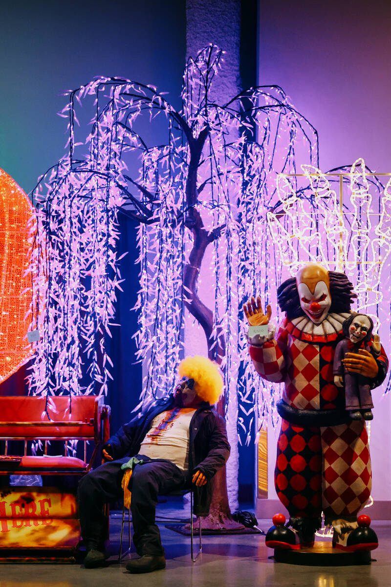 Clown statues sit at a booth in front of colorful lighting displays during the Halloween and Co ...