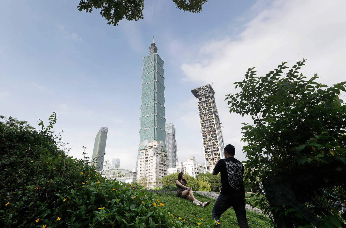 FILE - People take photos with the iconic Taipei 101 skyscraper in the background in Taipei, Ta ...
